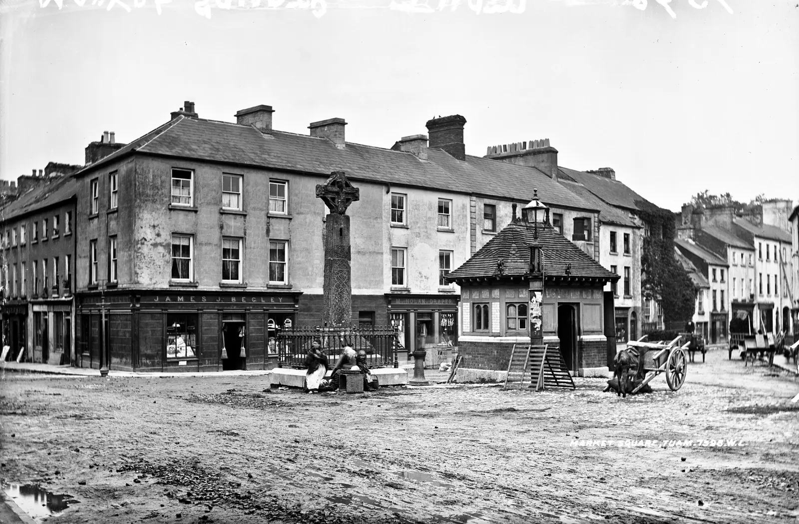 The Square, photographed by Robert French: the High Cross on its plinth, the Town Hall behind, carts where the cars now park